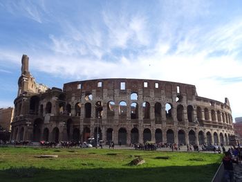 Low angle view of coliseum against cloudy sky