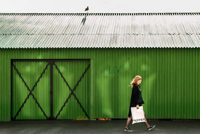 Full length of woman walking against wall