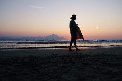 Full length of silhouette man standing on beach against sky during sunset