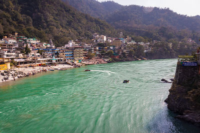 City at river bank with mountain background at day from flat angle