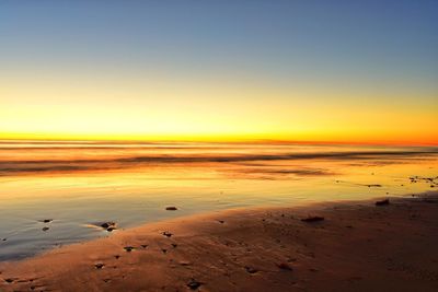 Scenic view of beach against clear sky during sunset