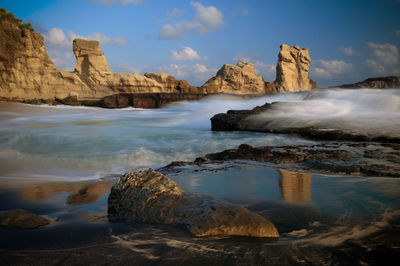 Scenic view of rocks on beach against sky