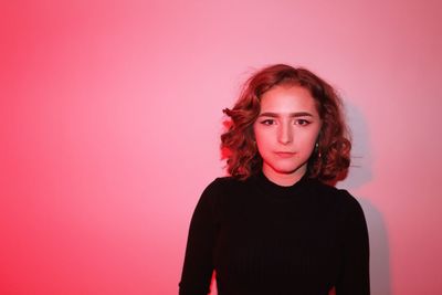 Portrait of beautiful young woman against red background