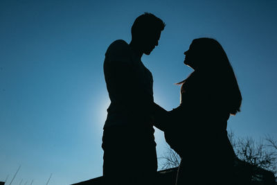 Silhouette of woman with arms outstretched against clear sky