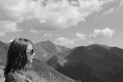 Side view of young woman on mountains against sky