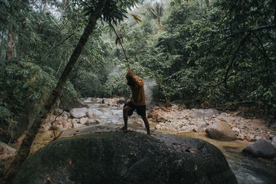 Full length of man on rock in forest