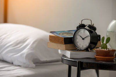 Close-up of alarm clock by bed on table at home