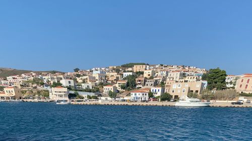 Townscape by sea against clear blue sky