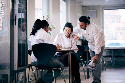 Multi-ethnic male and female chefs discussing menu in restaurant