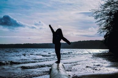 Full length of man with arms raised in sea against sky