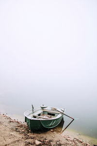 Boat moored on beach against sky