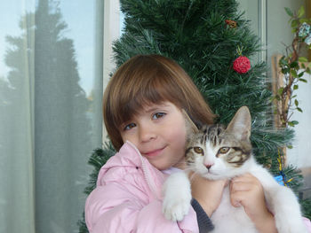 The little girl holds the kitten in her arms wishing a merry christmas