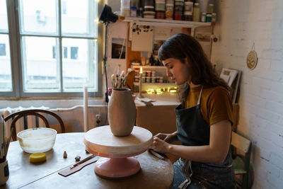 Creative woman shaping vase of clay at classes in art studio. female work with potter in workshop