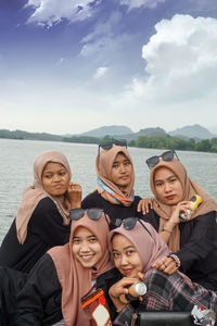 Portrait of smiling friends on beach against sky