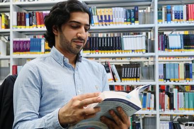 Mid adult man reading book in library