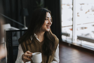 Portrait of smiling young woman holding coffee cup