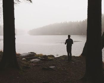 Man standing on lakeshore against sky