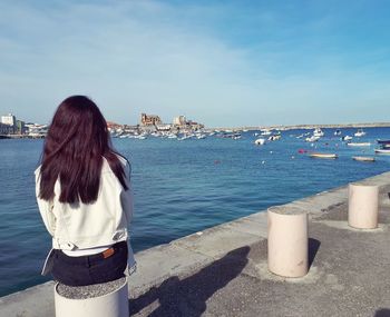 Rear view of woman standing by sea against sky