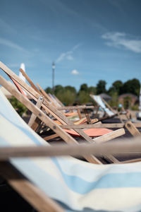 Close-up of deck chairs on table against sky
