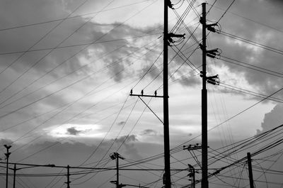 Silhouette power line against sky
