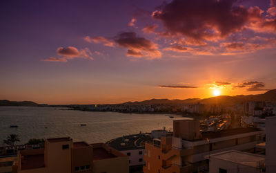 Town by sea against sky during sunset