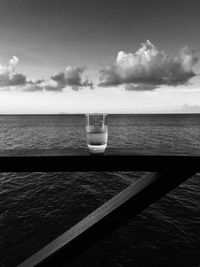 View of drink on table by sea against sky