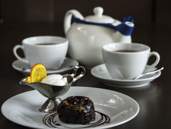 Close-up of chocolate fondant with cream and tea on table