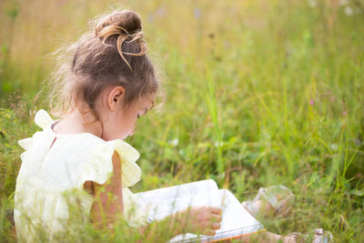 Rear view of girl sitting on grass