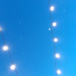 Low angle view of illuminated street light against blue sky