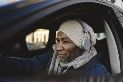 Mature man with wireless headphones traveling in car