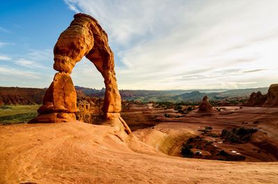 Rock formations on landscape against cloudy sky