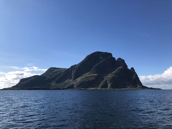 Scenic view of sea by mountain against sky