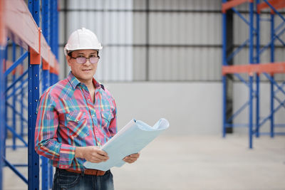 Portrait of man wearing hat standing at construction site