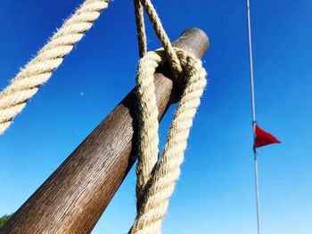 Low angle view of wooden post against blue sky