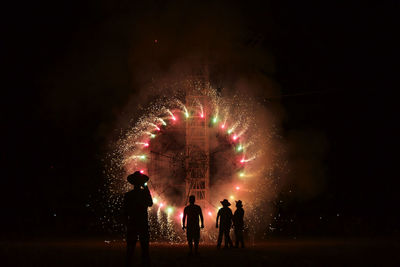 Silhouette people against fireworks at night