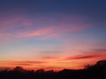 Low angle view of silhouette trees against dramatic sky