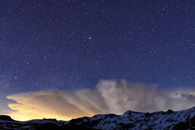 Scenic view of snowcapped mountains against sky at night