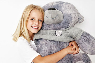 Portrait of young woman with teddy bear against white background