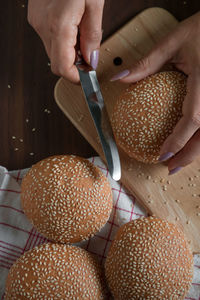 Cropped hands of woman cutting sesame seed buns