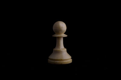 Close-up of chess pieces on table against black background