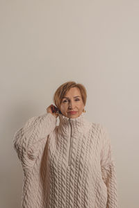 Portrait of young woman standing against wall