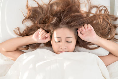 Young woman with long hair sleeping on bed at home