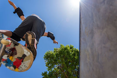 Low angle view of man performing stunt while skateboarding against sky