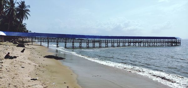 Pier on beach against sky