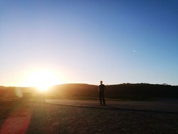 Full length of man standing on field against sky during sunset