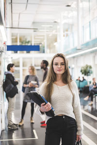 Portrait of confident female student standing in cafeteria at university