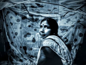 Portrait of woman sitting against fabric