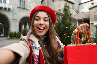 Portrait of smiling woman holding shopping bags outdoors