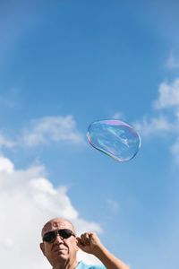 Low angle view of bubbles in mid-air against sky