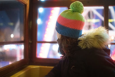 Close-up of woman wearing knit hat looking through window